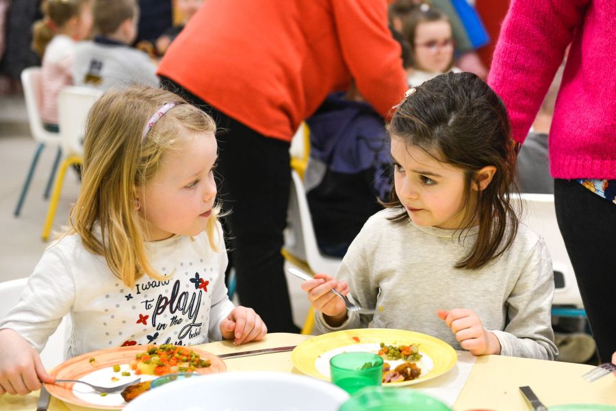 Deux élèves de maternelle partagent leur repas au restaurant scolaire