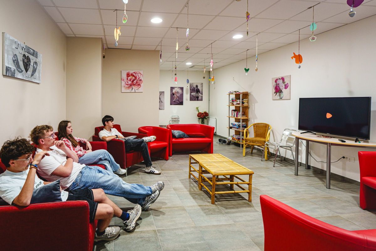 Coin salon avec fauteuils rouges et télévision dans l'espace de vie de l'internat