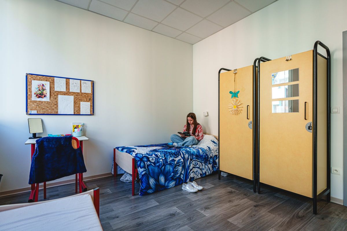Interne assise sur son lit dans une chambre aménagée de l'internat