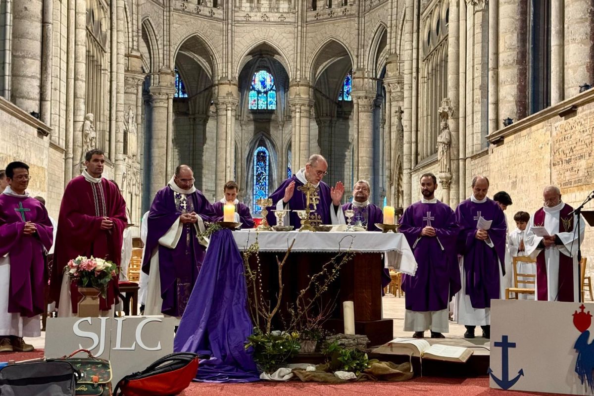 Célébration eucharistique présidée par un évêque, panneau SJLC visible au premier plan