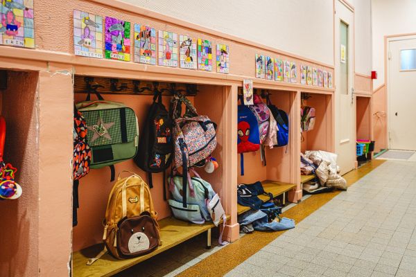 Vestiaire de la classe de maternelle avec cartables suspendus aux patères