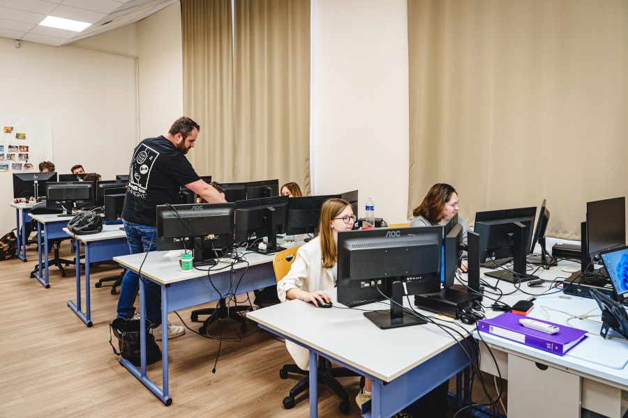 Formateur accompagnant individuellement un étudiant en salle informatique du Bachelor Communication
