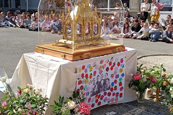 Reliquaire fleuri de sainte Thérèse entouré d'élèves recueillis dans la cour