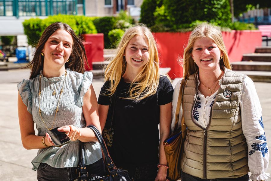 Trois lycéennes souriantes dans la cour de l'établissement au soleil