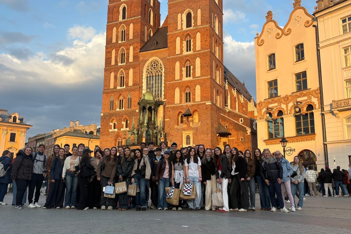Groupe de lycéens en voyage scolaire devant une basilique gothique à Cracovie