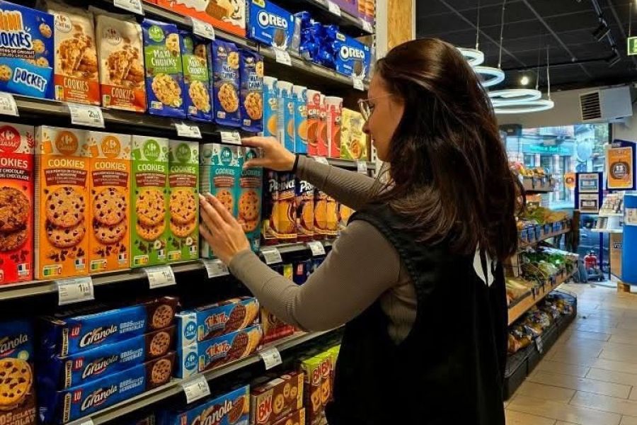 Une apprentie réapprovisionne les rayons de biscuits dans un supermarché