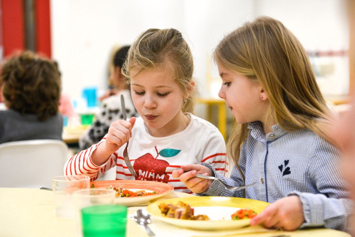 Deux écolières partagent un repas et discutent ensemble à la cantine