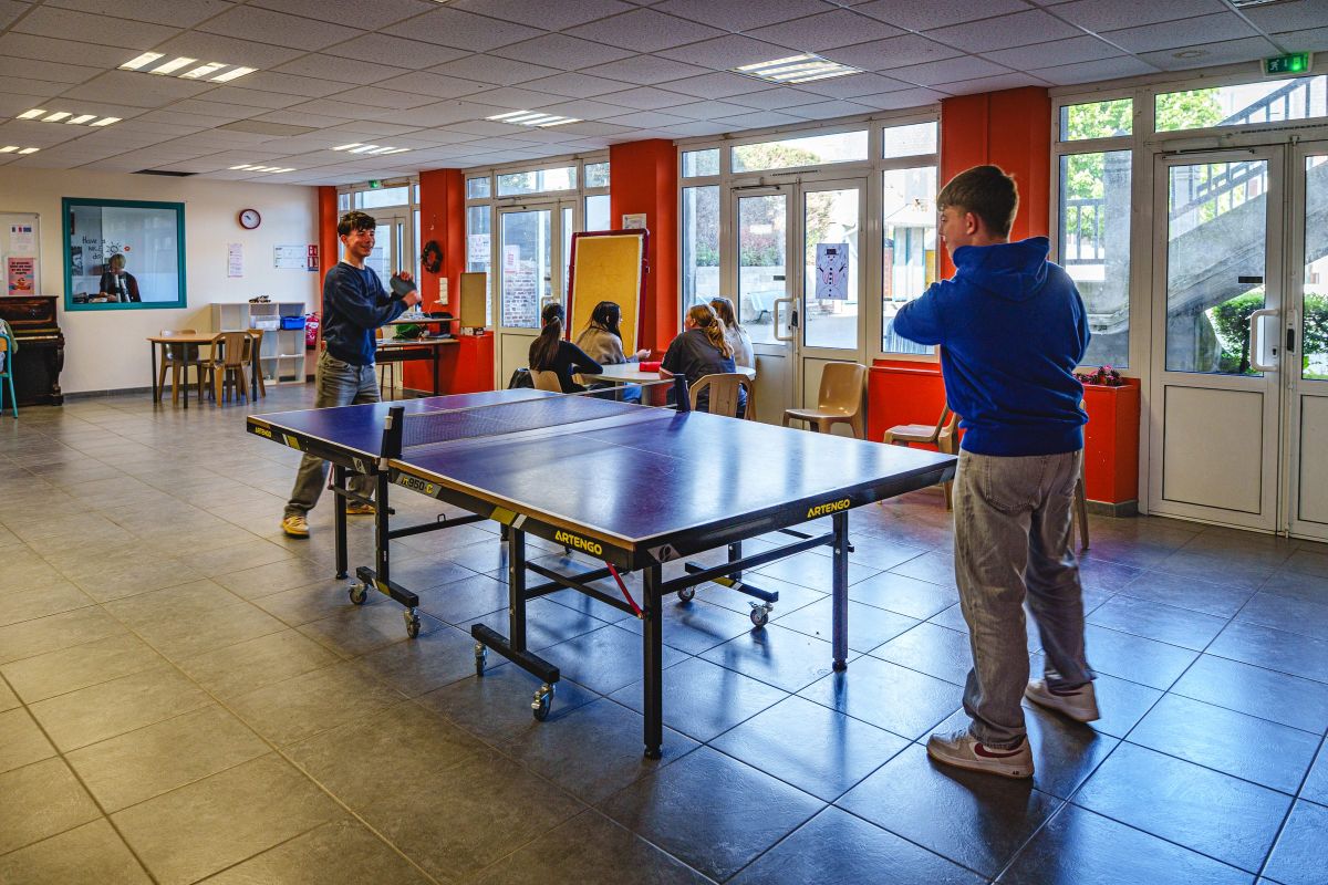 Collégiens jouant au tennis de table dans un espace de vie commun du collège