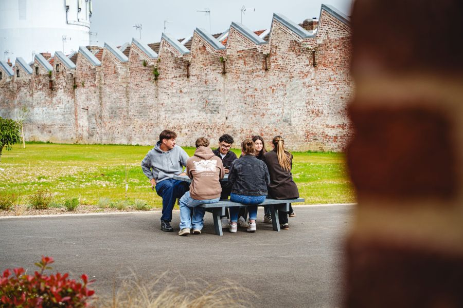 Étudiants du Sup' Saint Jean assis sur un banc devant le mur du campus