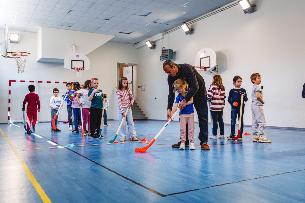 Séance de hockey en salle avec des élèves et un intervenant sportif