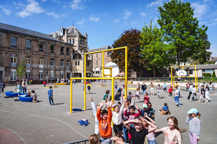 Récréation dans la cour de l'école avec ses cages de but jaunes