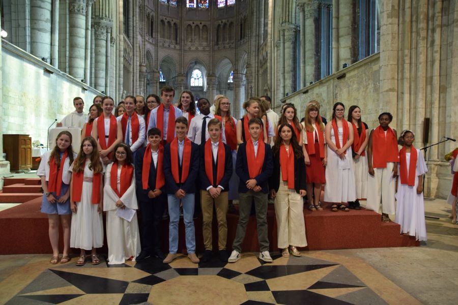 Jeunes en aube et écharpe rouge posant dans la cathédrale après leur profession de foi