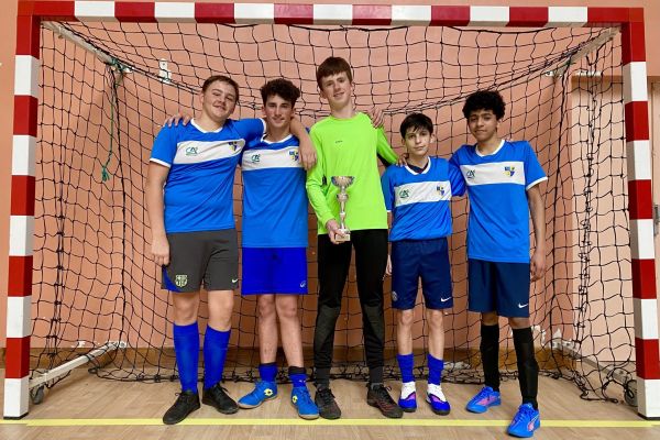 Équipe garçons de futsal posant avec leur coupe devant les cages