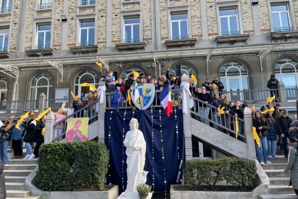 Rassemblement festif sur un escalier monumental avec bannières et statue