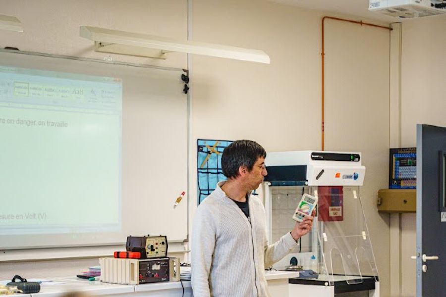 Professeur présentant un dispositif électronique à des élèves en classe