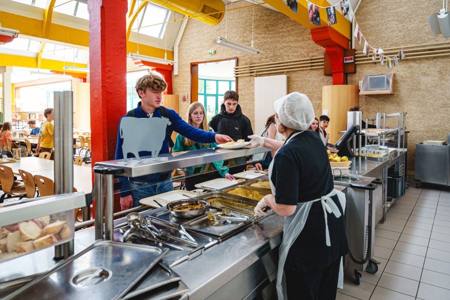 Élève servi à la ligne de self du restaurant scolaire du collège