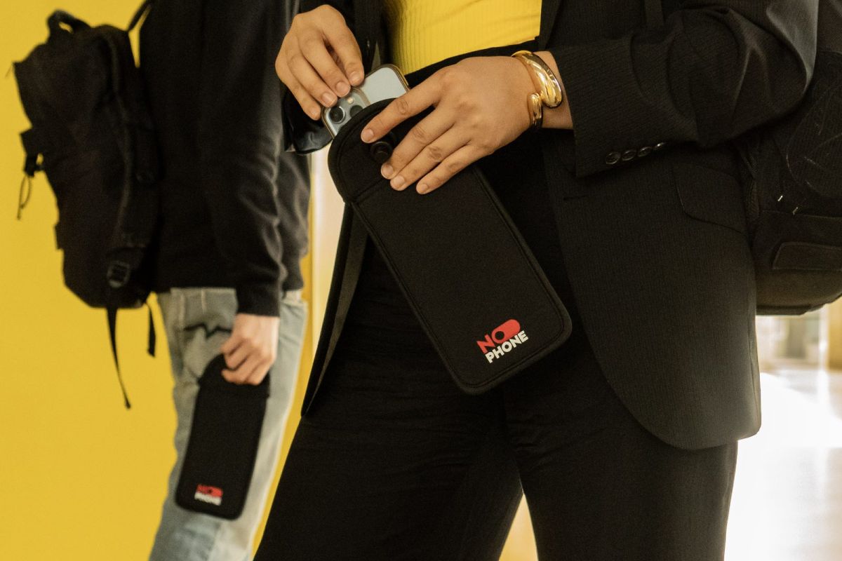 Élève tenant une pochette NoPhone dans un couloir du collège aux murs jaunes