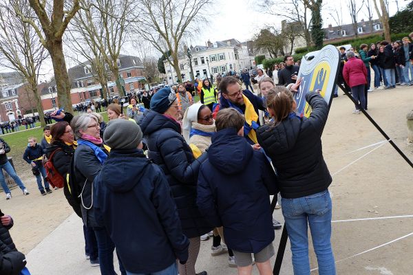 Groupe d'élèves et de familles réunis autour d'une grande composition dans un parc