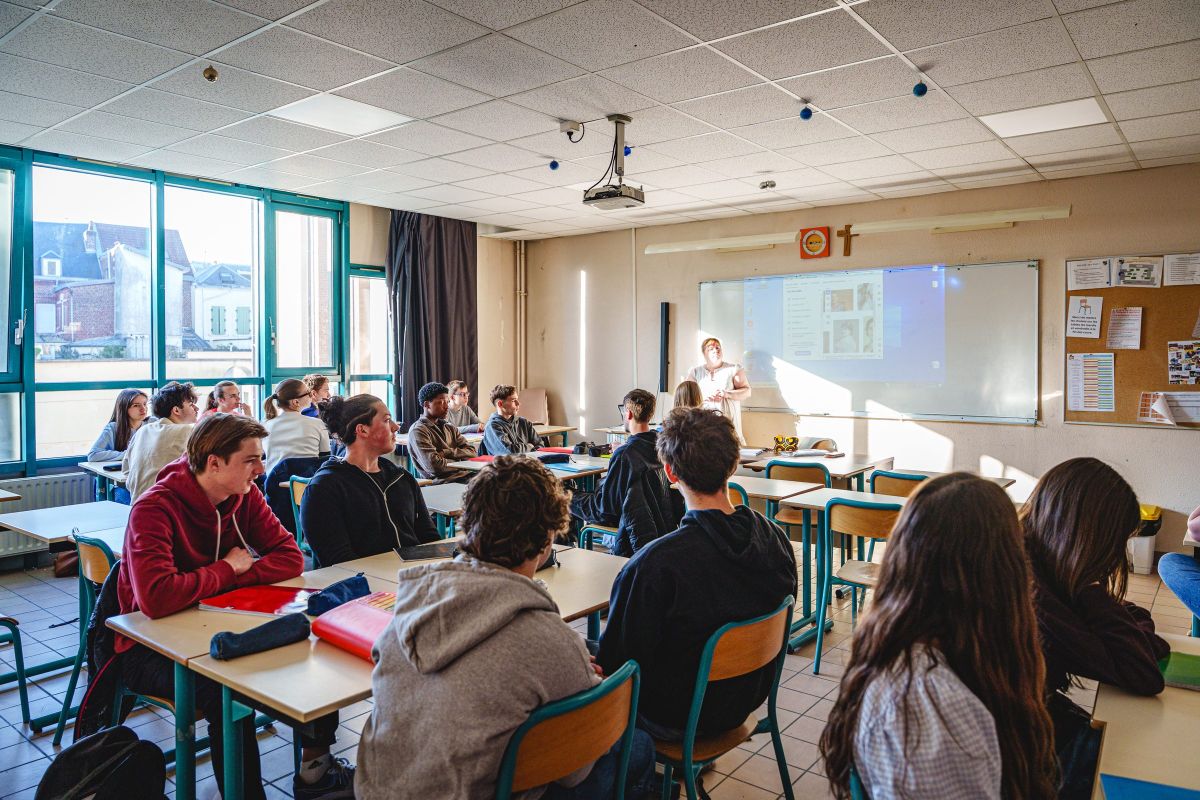 Lycéens suivant un cours devant le tableau numérique en classe