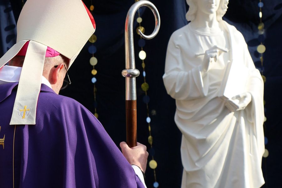 Évêque en procession devant une statue du Christ lors d'une célébration diocésaine