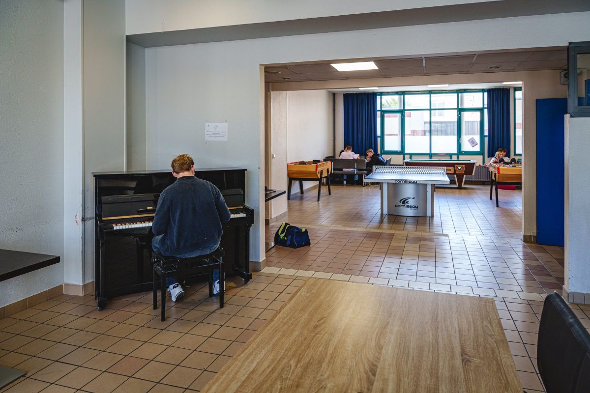 Élève jouant du piano dans le foyer de vie des internes du lycée