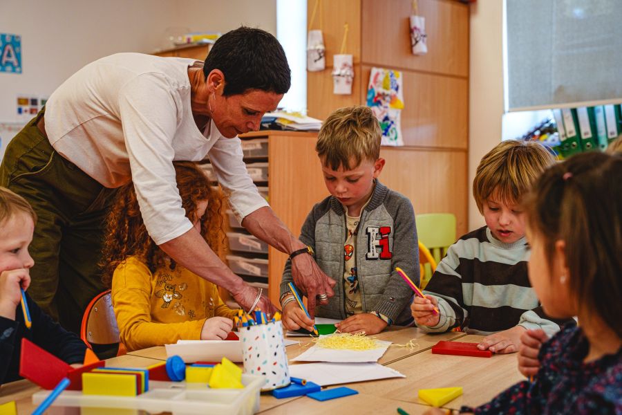 Enseignante aidant des enfants pour une activité manuelle en classe