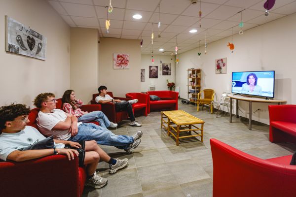 Élèves de l'internat jouant aux cartes dans un salon aux fauteuils bleus