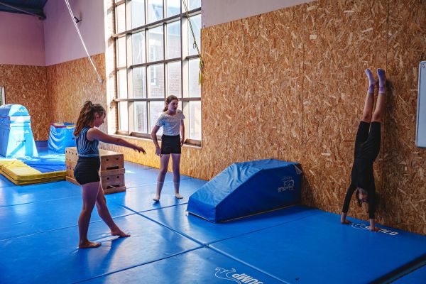 Jeunes gymnastes s'entraînant à la roue et à l'appui renversé en salle