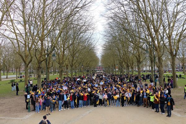 Grand rassemblement d'élèves portant des foulards jaunes et bleus dans une allée arborée