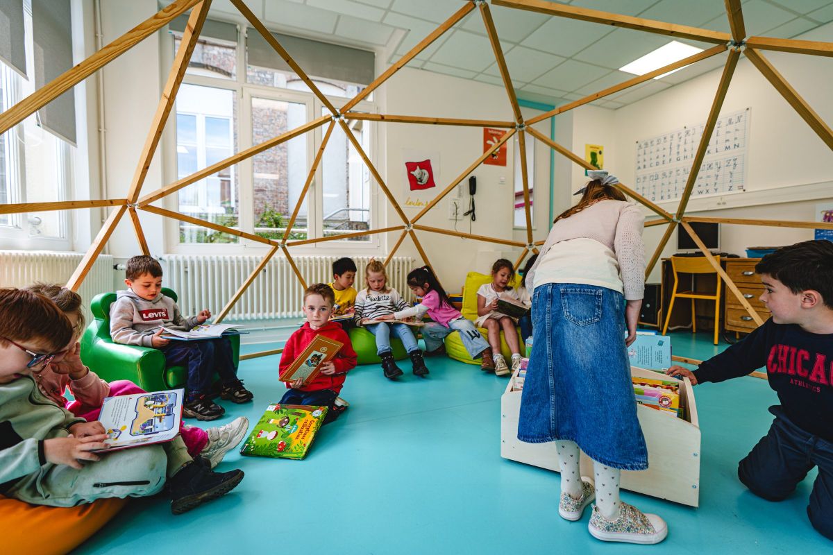 Élèves de primaire en atelier lecture sous une structure géodésique en classe
