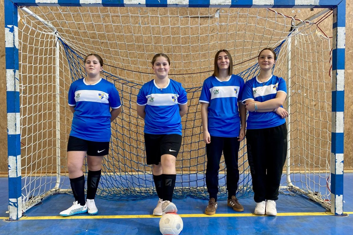Équipe féminine de futsal posant devant les cages en tenue bleue