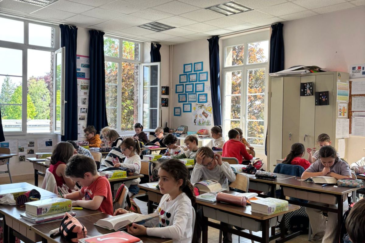 Élèves de primaire en lecture silencieuse à leur bureau dans la classe