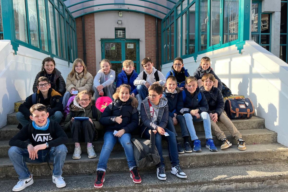 Élèves de CM2 assis sur les marches devant l'entrée du collège lors d'une visite