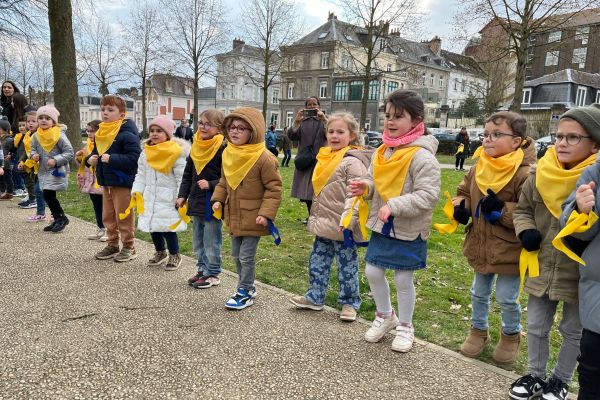 Écoliers en foulards jaunes alignés le long d'une allée pour un événement