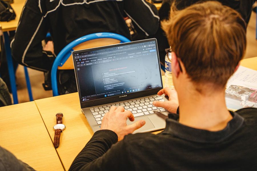 Un étudiant en alternance prend des notes sur son ordinateur portable en cours