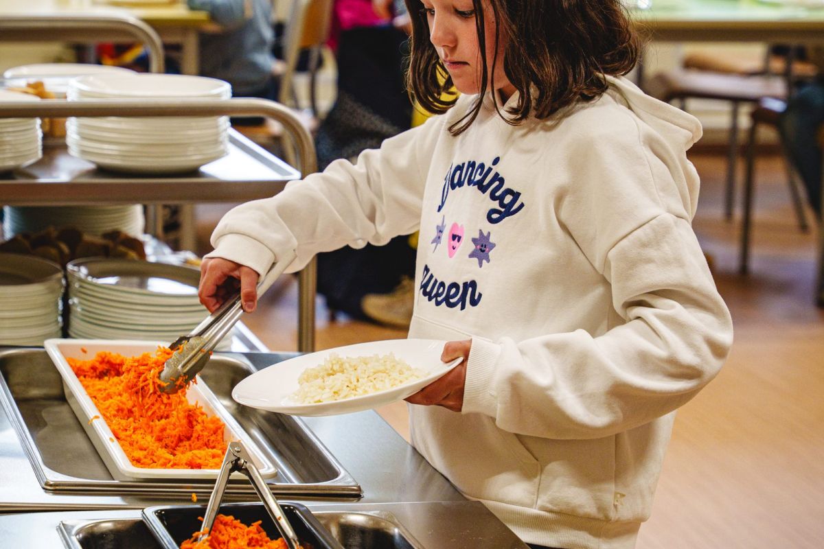 Une élève se sert des crudités au buffet self-service de la cantine
