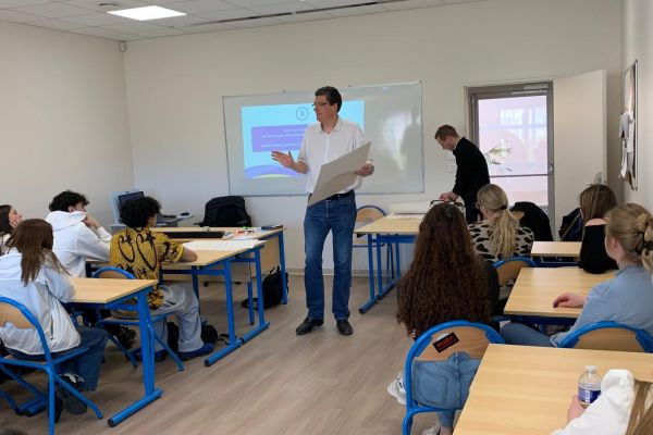 Intervenant échangeant avec des étudiants du supérieur en salle de classe
