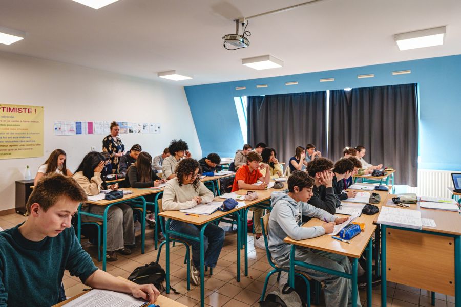 Élèves du collège installés à leur bureau pendant un cours en classe