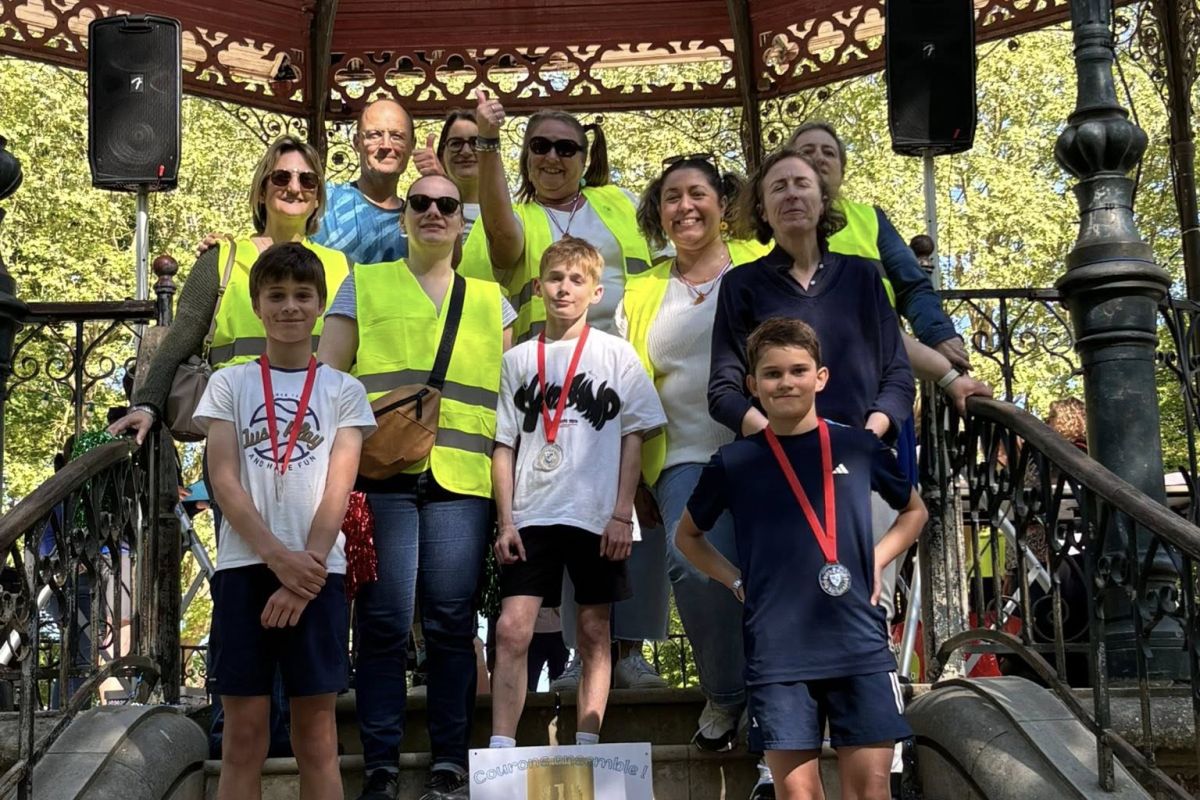 Jeunes médaillés entourés d'accompagnateurs sur un kiosque après une course