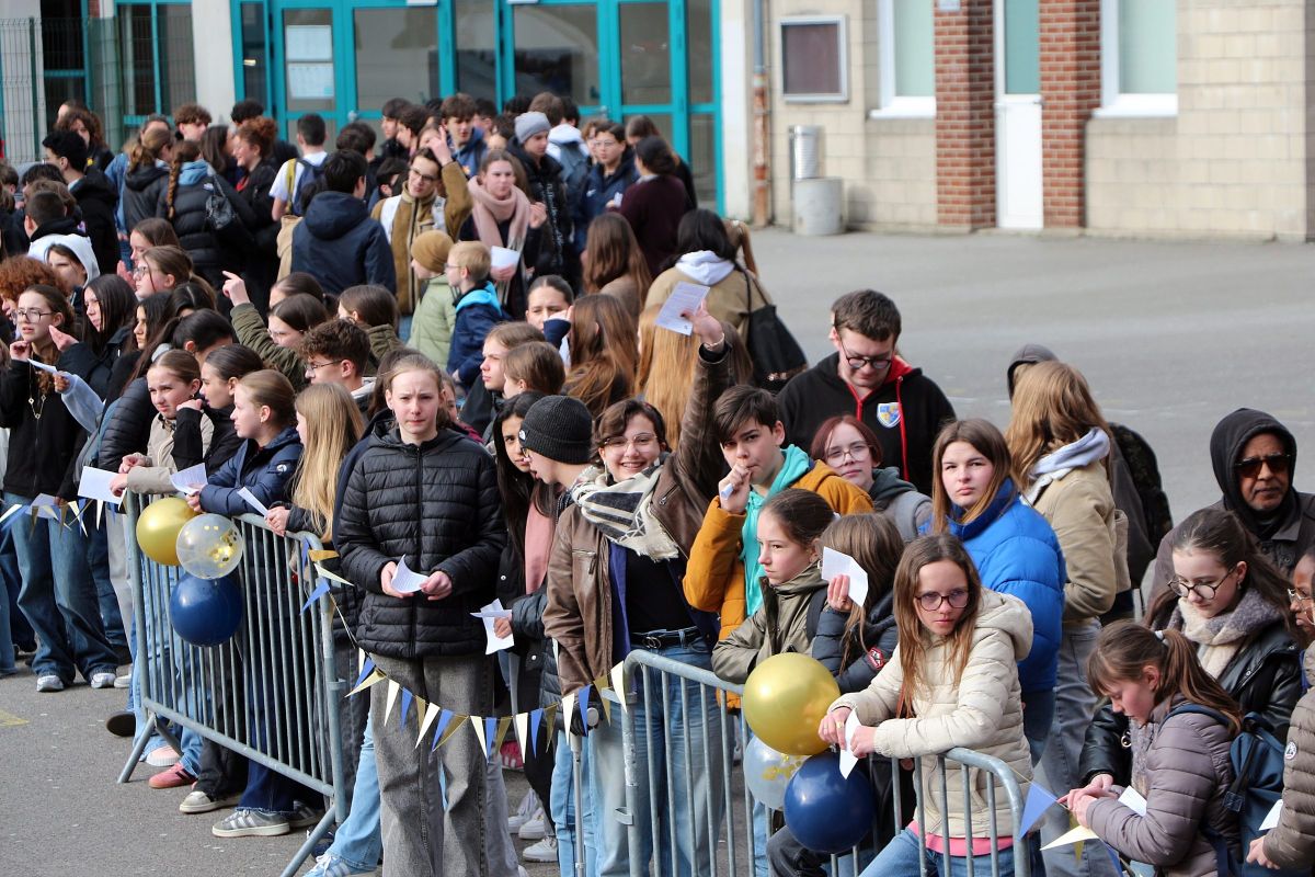 Foule d'élèves rassemblée le long de barrières pour un événement festif